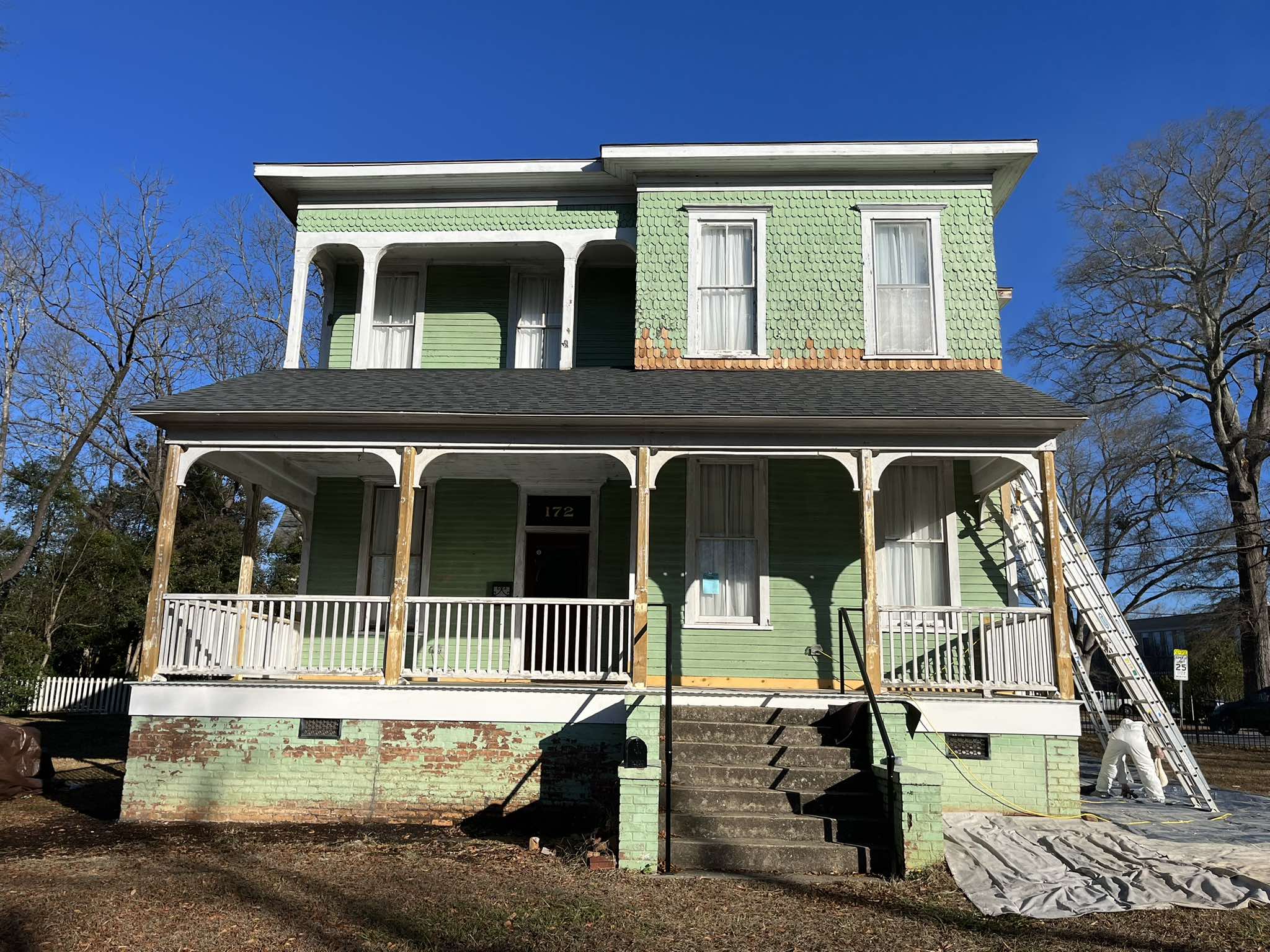 Front elevation before painting with green siding and weathered porch and foundation surfaces