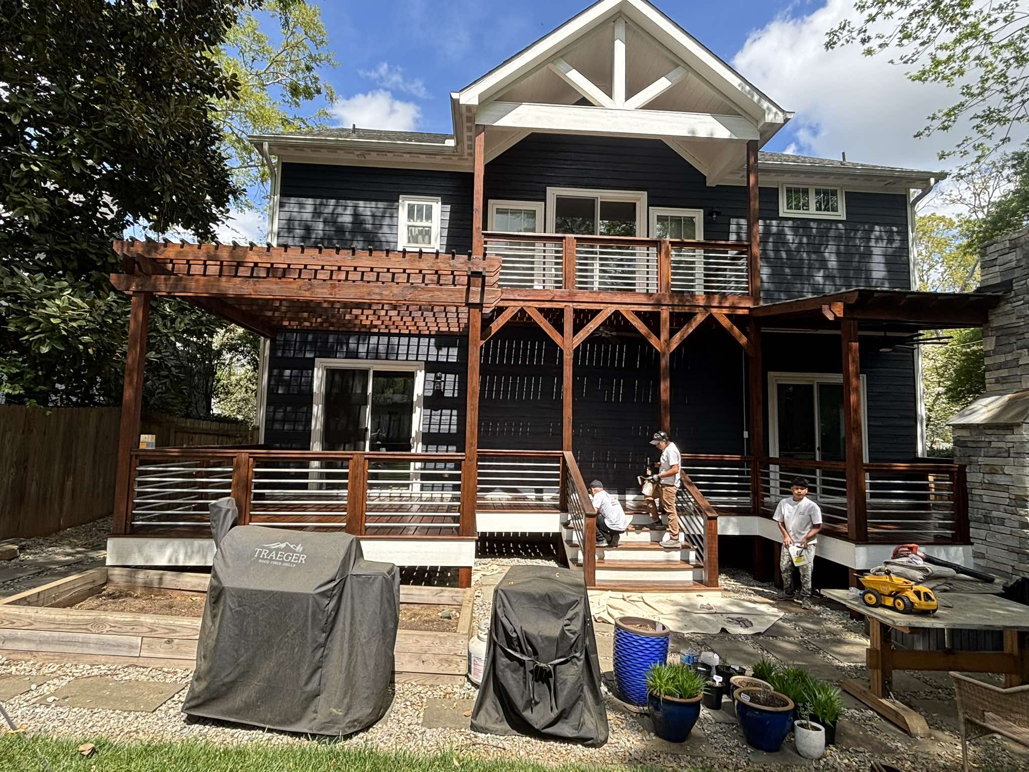 Painting crew working on the stained deck stairs, railings, posts, and pergola structure