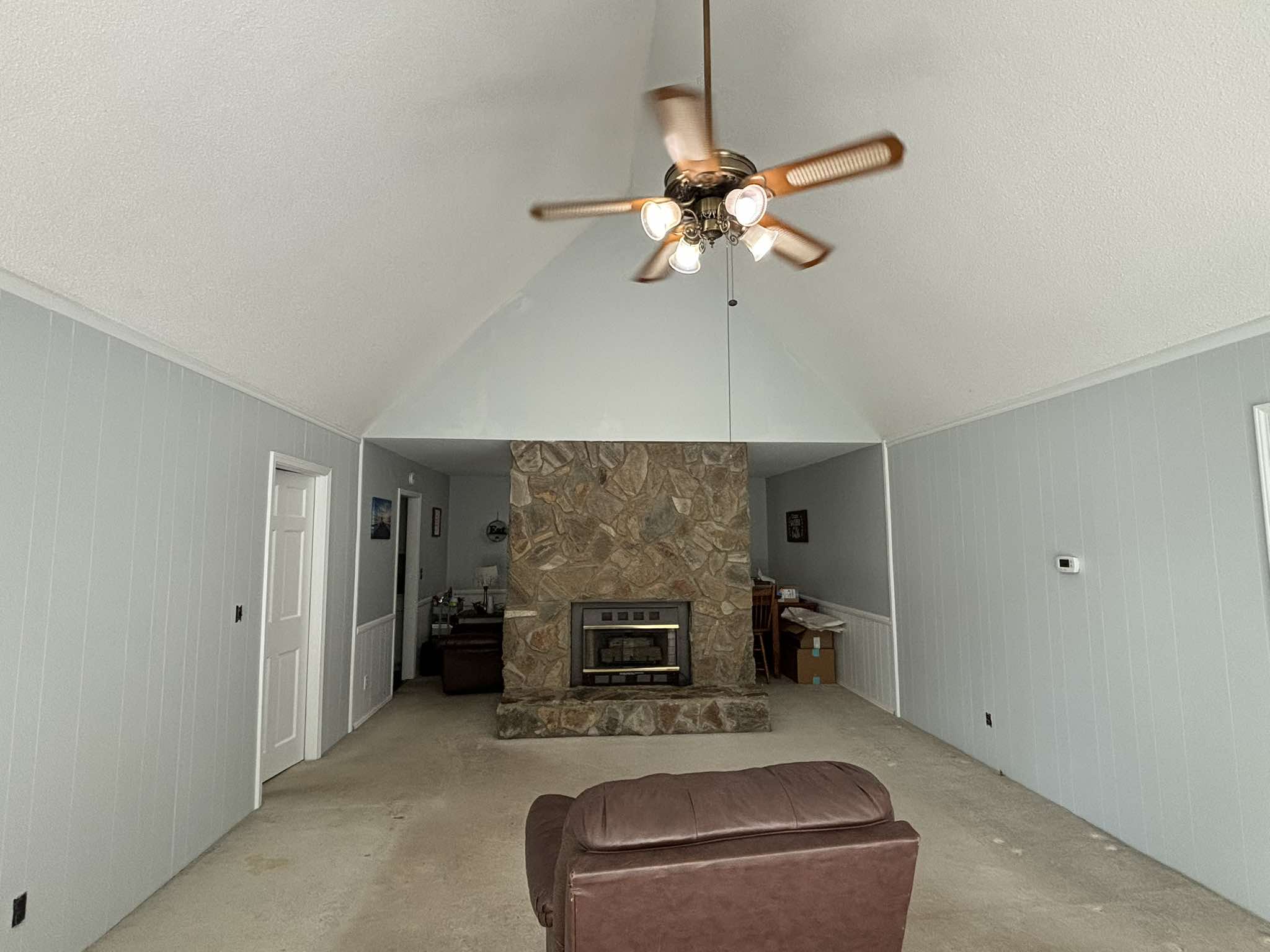 Finished vaulted room with soft gray walls, bright trim, and a stone fireplace