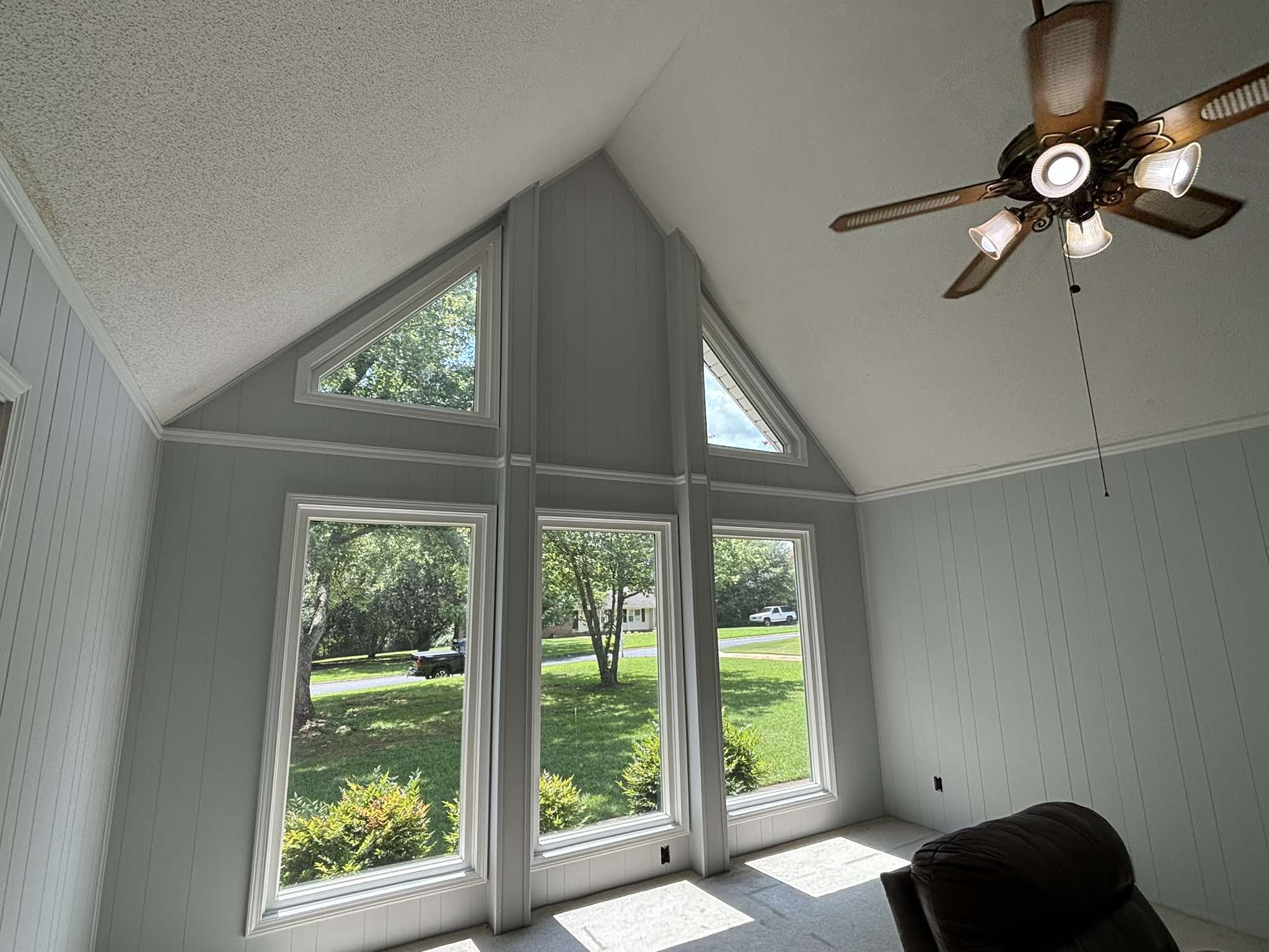 Finished triangular window wall with soft gray paneling and crisp white window trim
